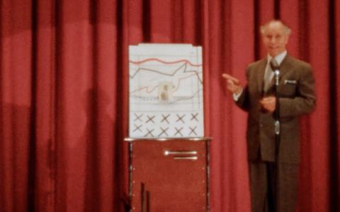 Man in suit sanding behind a flipchart with nonsensical illustration